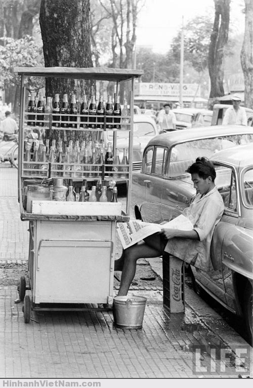 Cậu bé bán nước lấy khay nước ngọt làm ghế ngồi