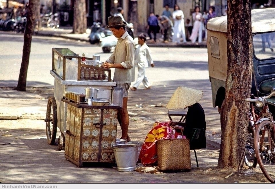 Một xe đẩy bán nước bên cạnh một quầy cà phê nhỏ trên vỉa hè Sài Gòn
