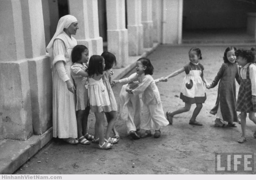 Một bà sơ người Pháp chơi đùa với trẻ em tại nhà thờ Lớn Hà Nội